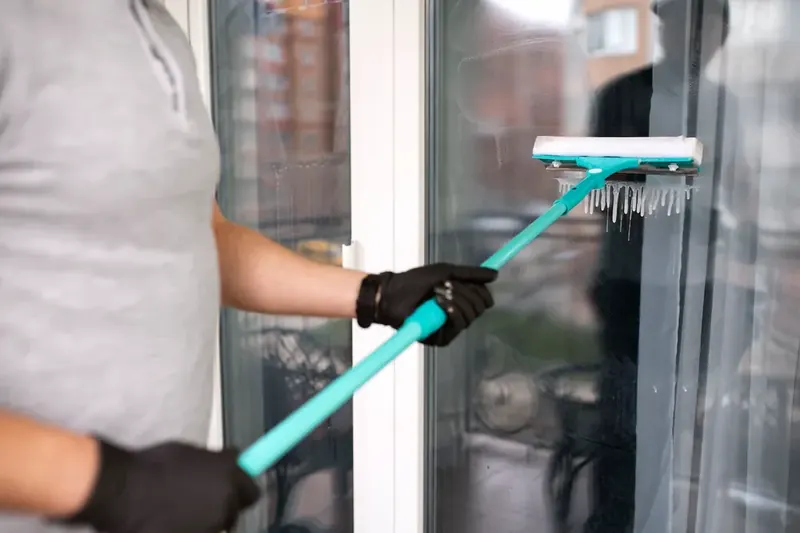 Window cleaner using an extension-pole squeegee to reach an exterior window pane
